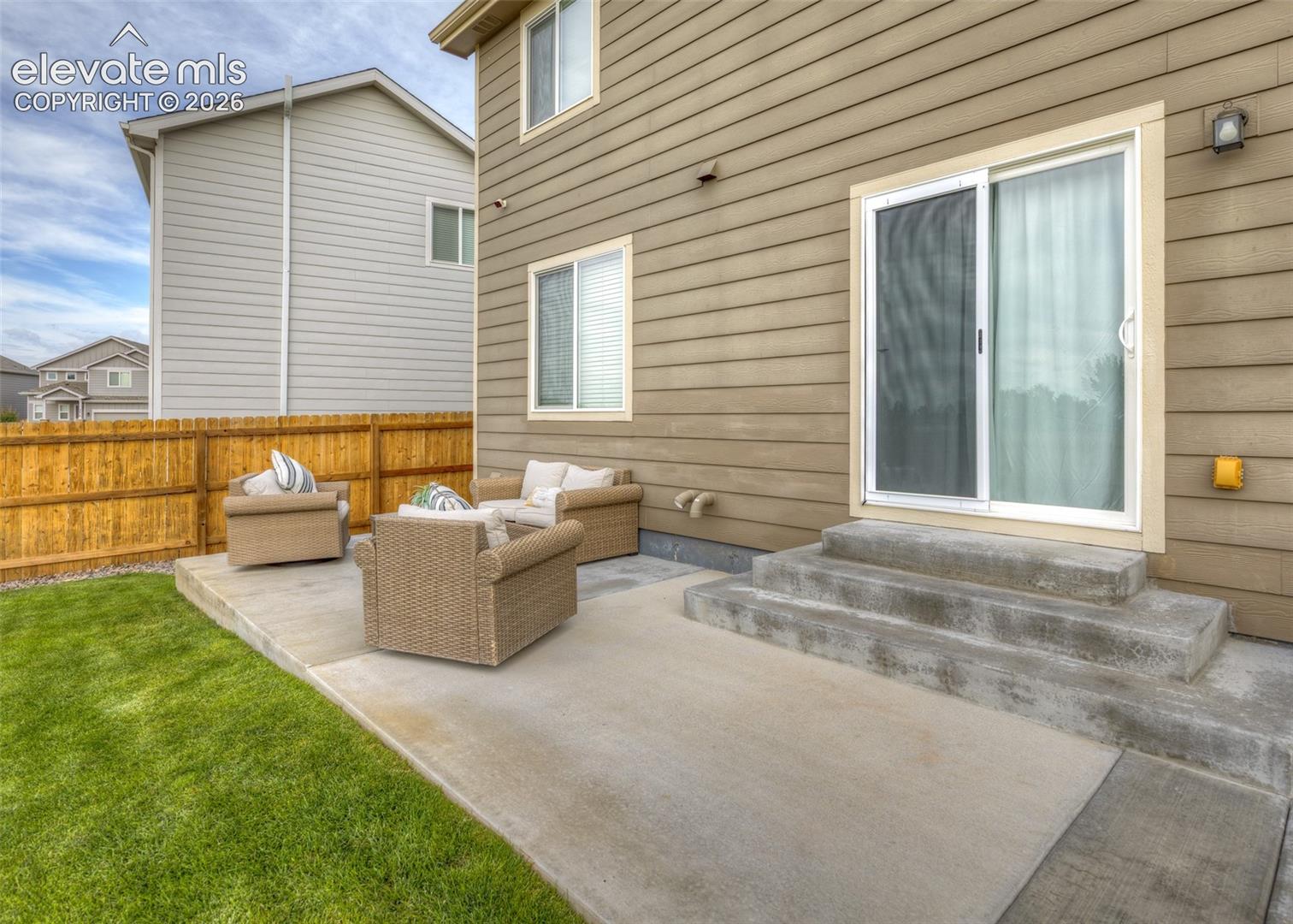 Exterior featuring horizontal lap siding, a concrete patio, sliding glass door, and a wood privacy fence