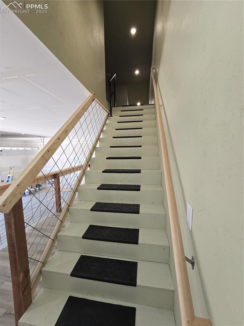 Garage stairway featuring hardwood / wood-style flooring