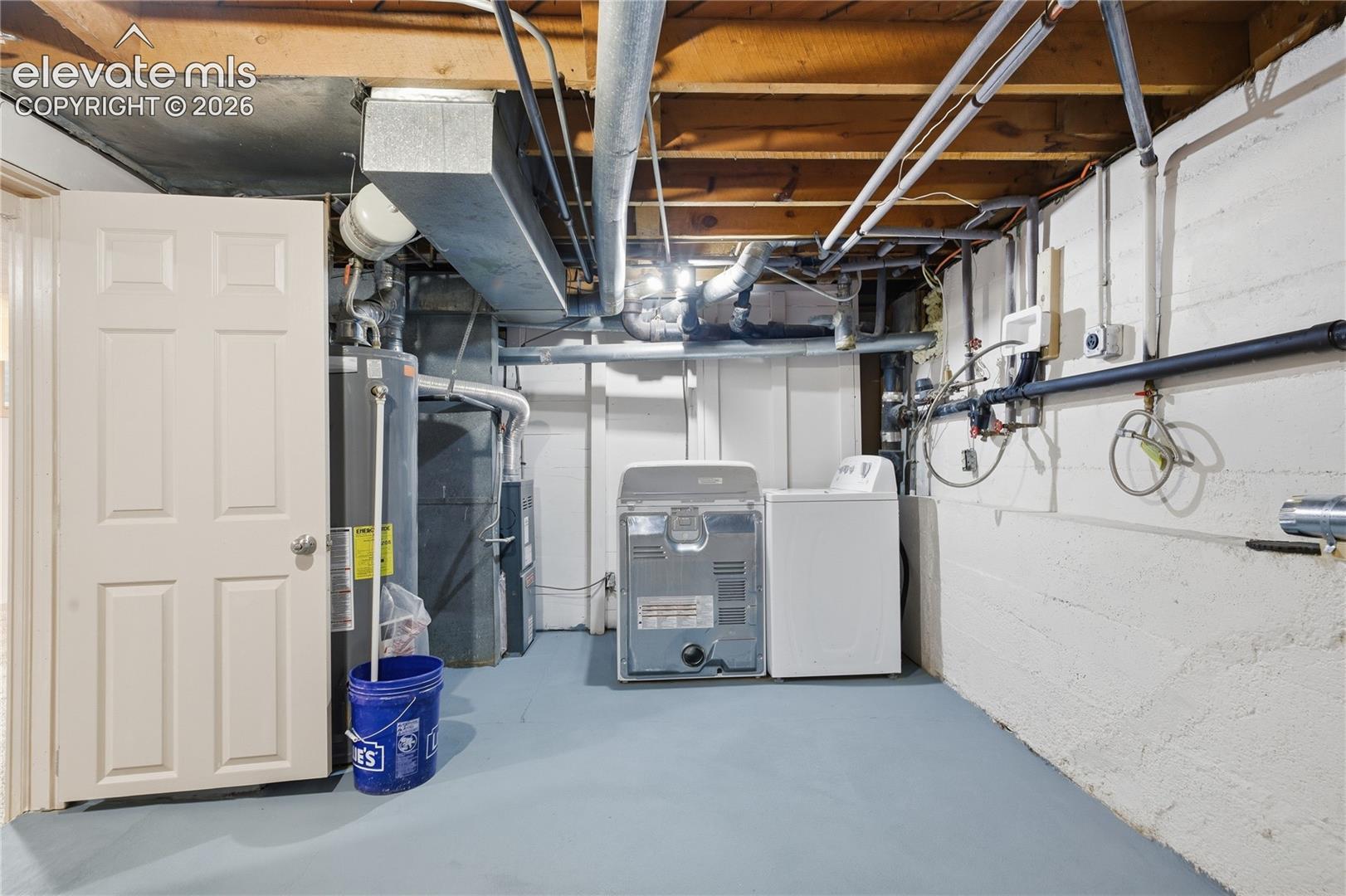 Utility space featuring a painted concrete floor, exposed joist ceiling, painted masonry walls, and designated laundry hookups
