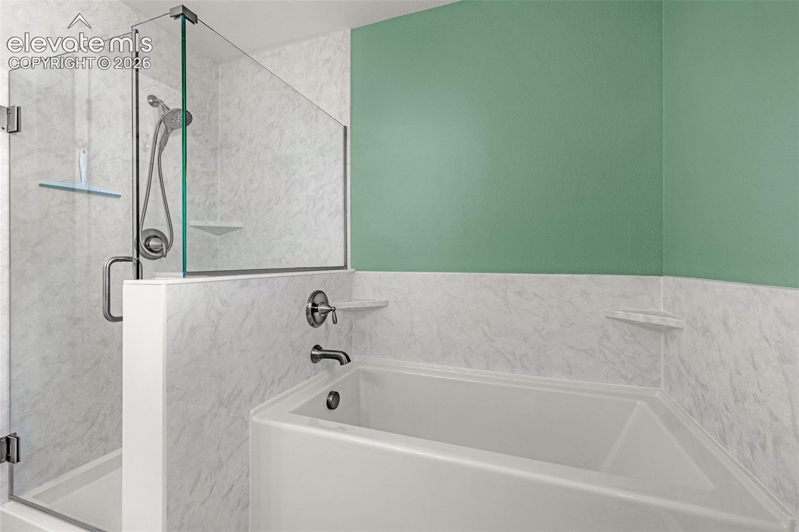 Soaking tub with integrated wall surround, glass-enclosed shower, polished chrome plumbing fixtures, and built-in corner shelving