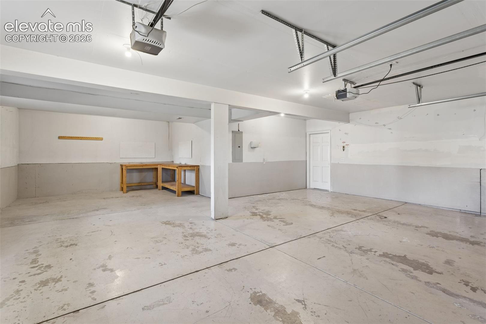 Spacious garage featuring a concrete floor, overhead lighting, and white paneled door