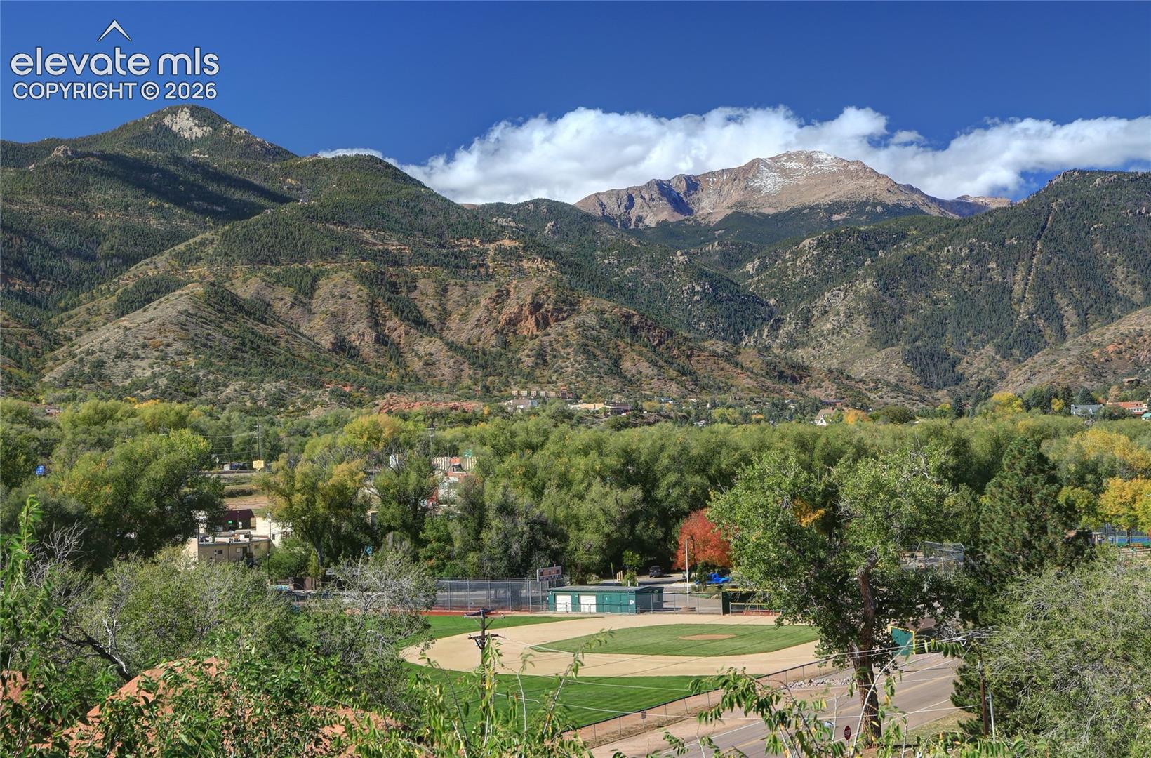 Expansive mountain backdrop featuring mature trees and a baseball field