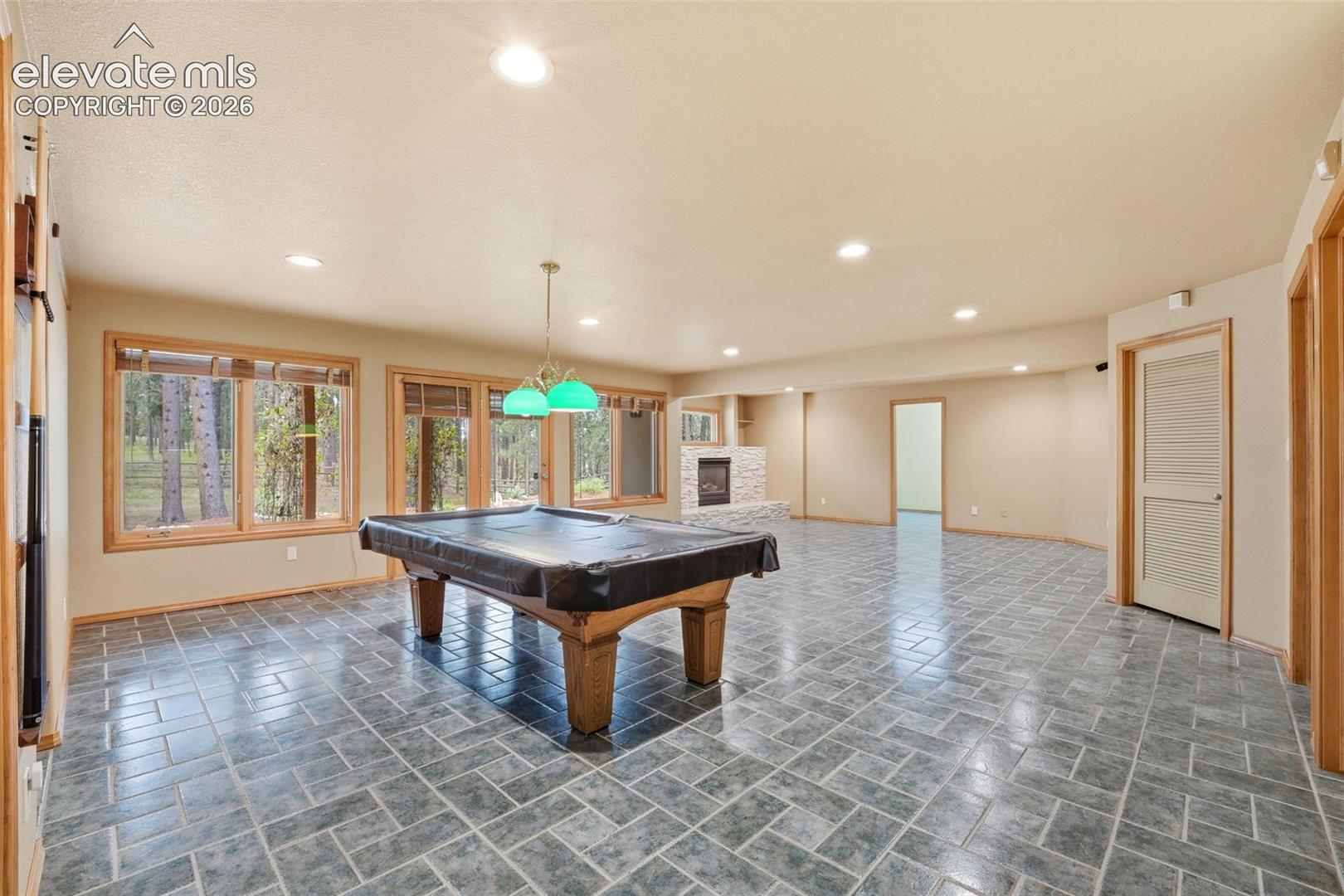 Spacious recreational room featuring gray tile flooring and recessed lighting