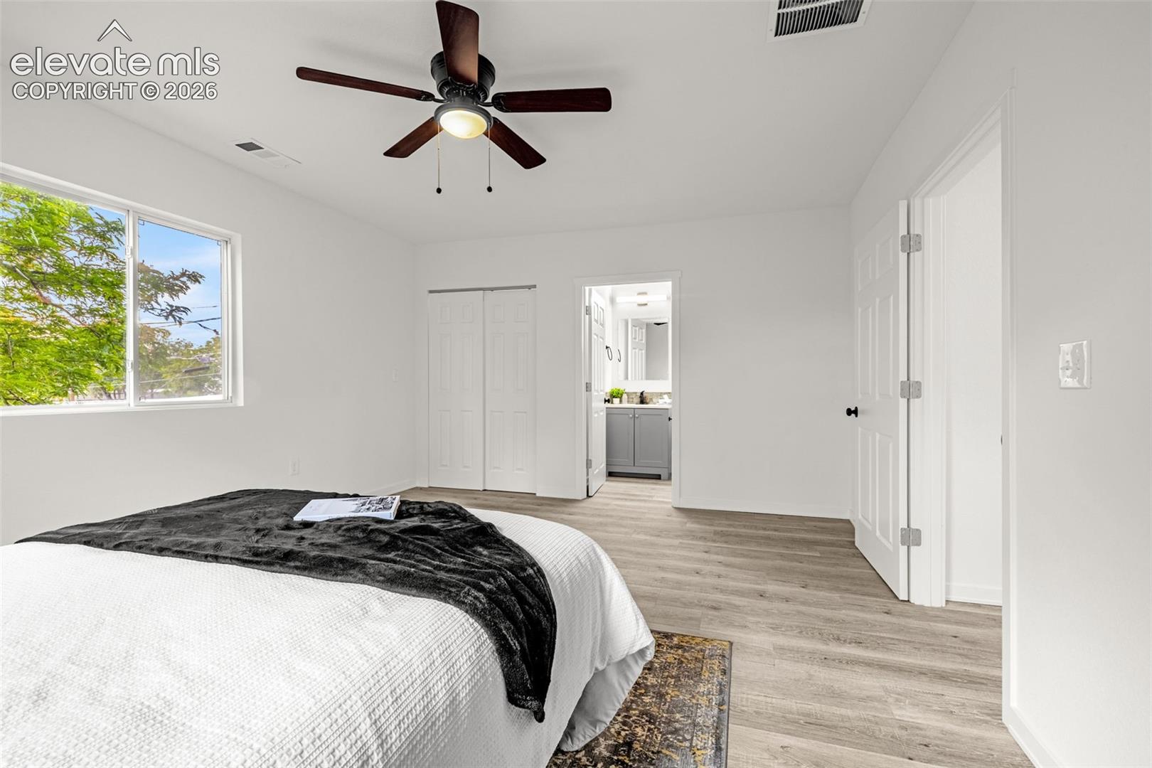 Bedroom featuring light wood-finish flooring, white walls, and a contemporary ceiling fan with integrated lighting