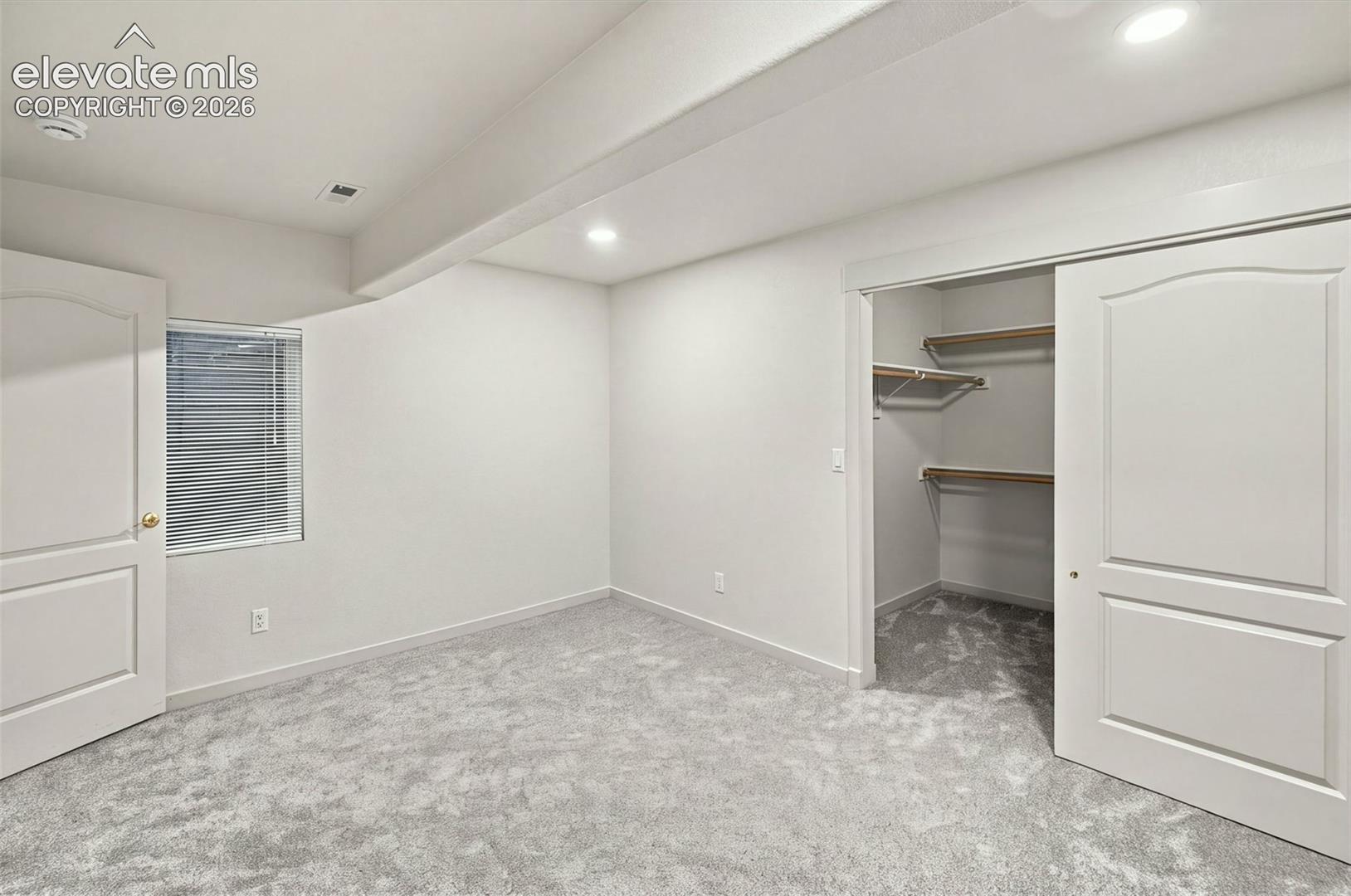 Interior space featuring neutral wall tones, carpeted flooring, recessed lighting, and a walk-in closet with built-in shelving