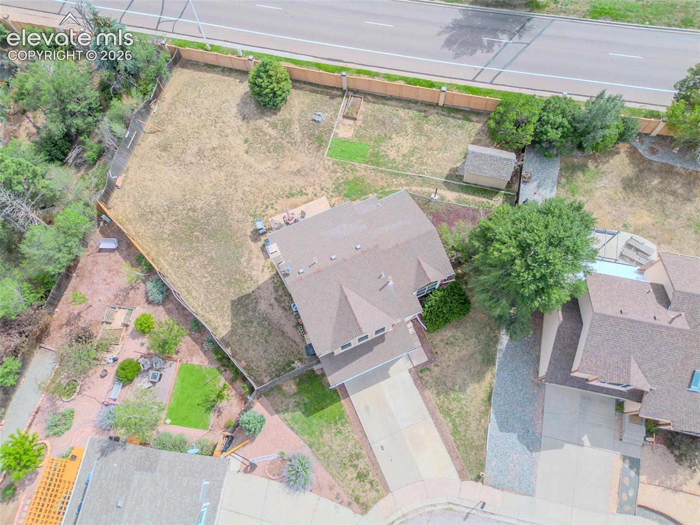 Expansive property featuring a multi-level roofline, extensive driveway, and a fenced backyard with mature landscaping