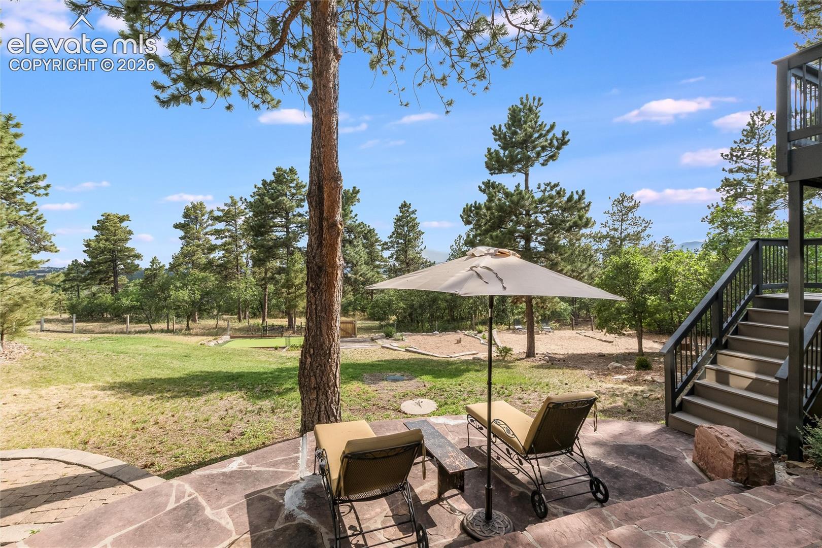 Stone patio with irregular flagstone pavers, surrounded by mature trees and a natural landscape