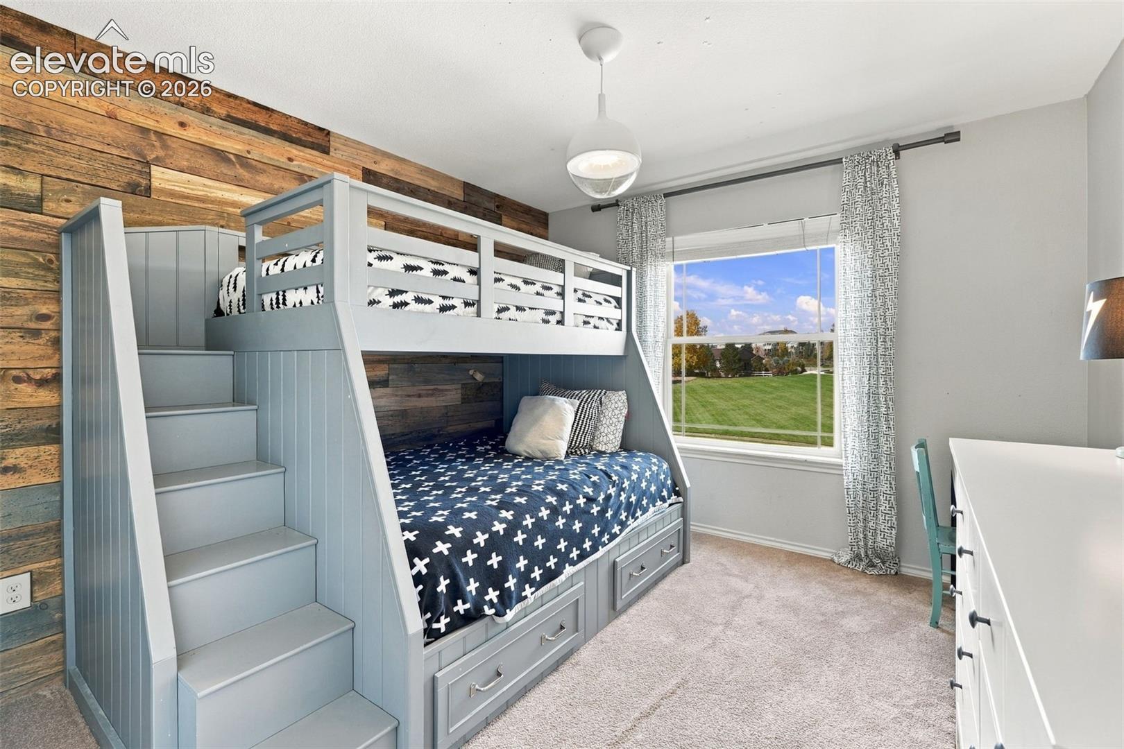 Accent wall featuring wood plank paneling, custom built-in bunk bed with integrated storage drawers and staircase, and overhead globe pendant lighting