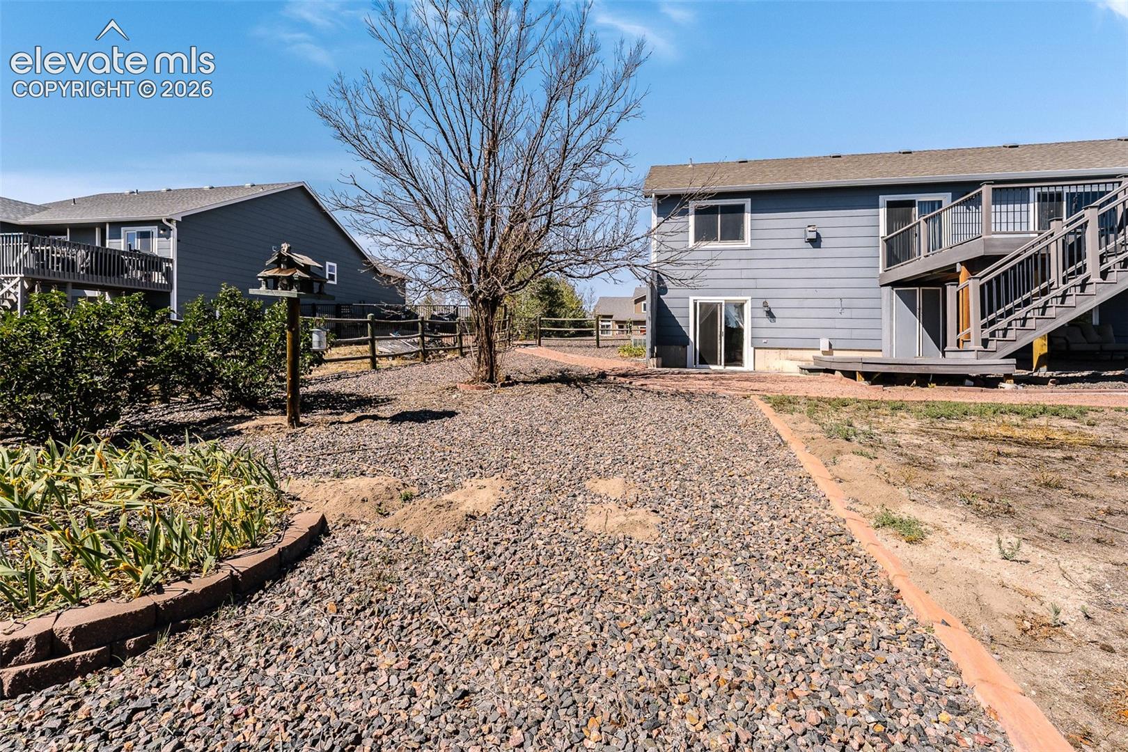 Low maintenance xeriscaped yard with mature trees, walkways, planters, and grass area.