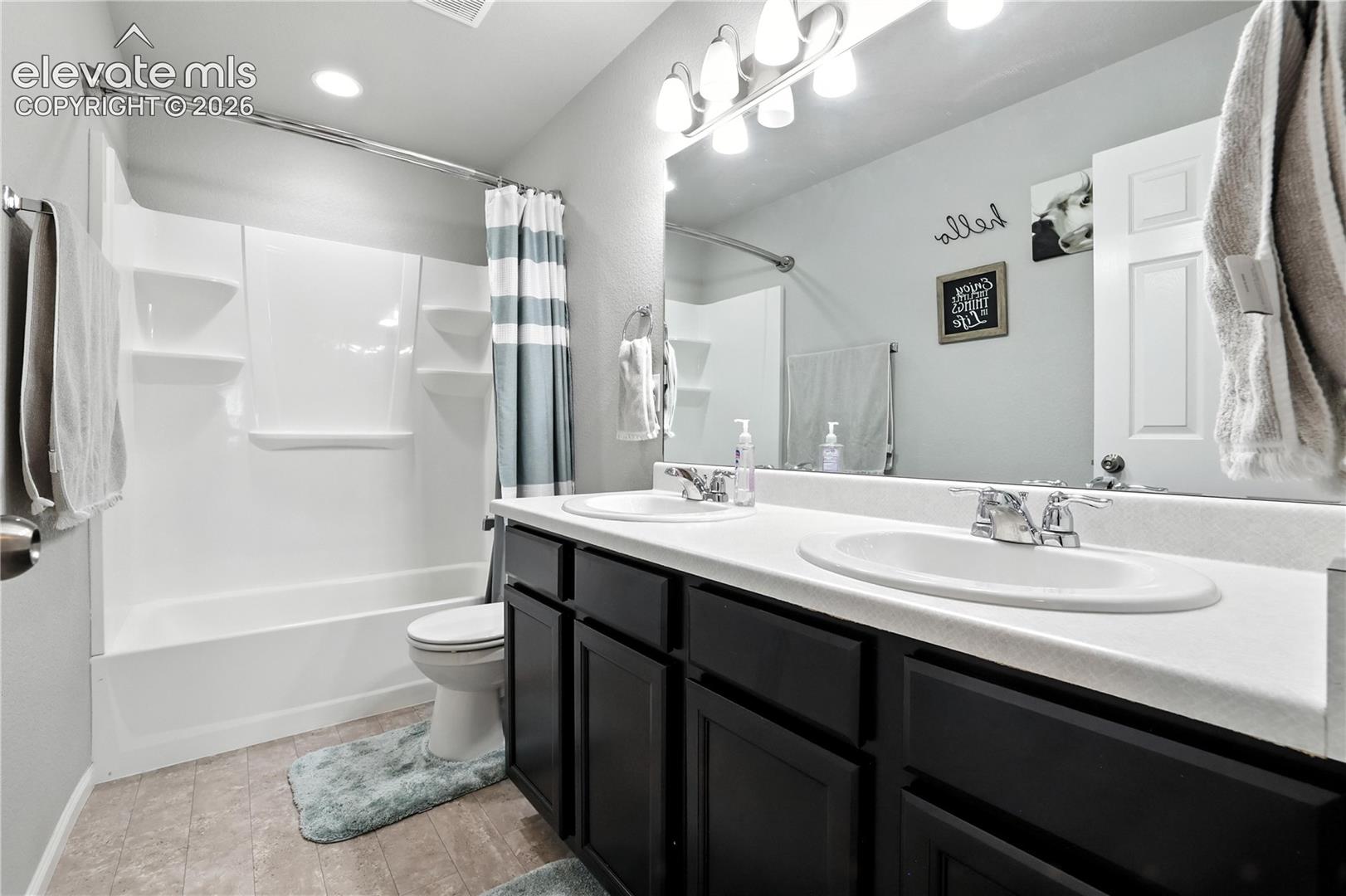 Double vanity with integrated sinks, dark wood-finish cabinetry, and an expansive mirror