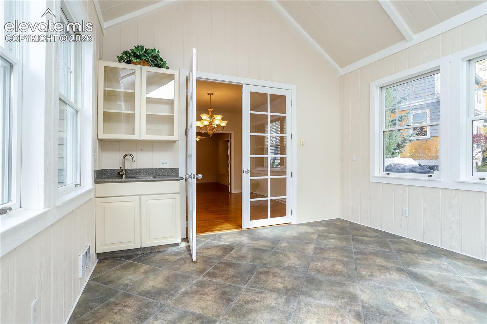 This wonderful sun room features a wet bar area and tile flooring.