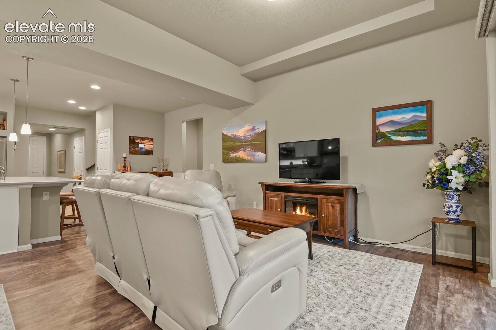 Living area featuring wood-finish luxury tile flooring, tray ceilings, recessed lighting, and pendant lighting