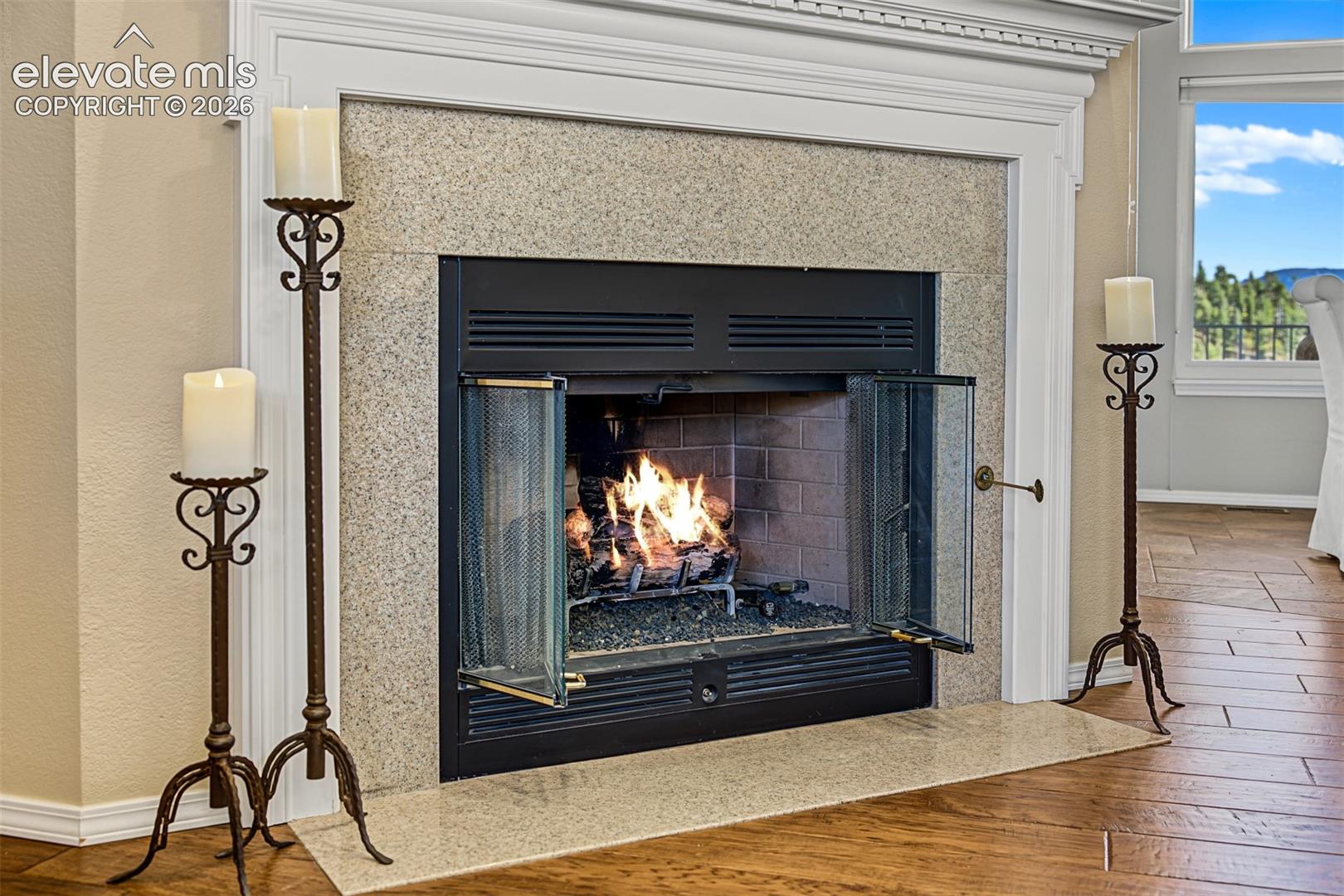 Elegant gas-burning fireplace featuring a stone surround, detailed white mantel, and warm hardwood flooring.