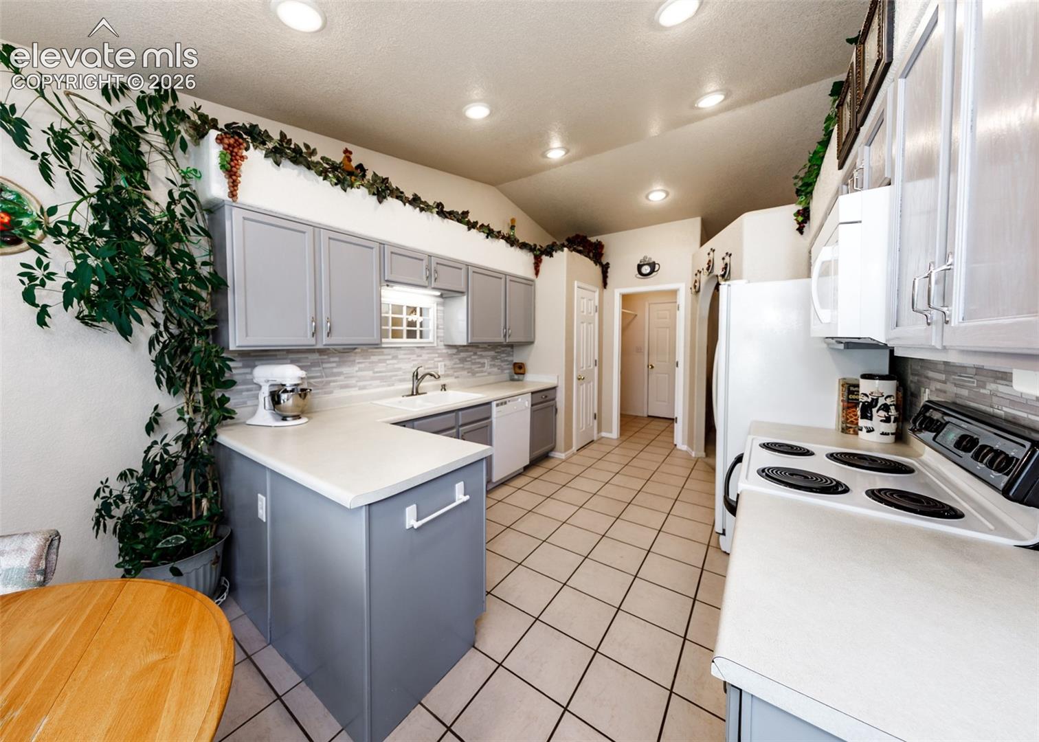 Kitchen featuring painted cabinetry, tiled backsplash, recessed lighting, and tile flooring