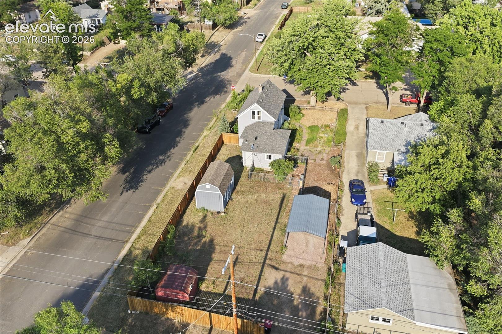 Property featuring a detached shed, an additional smaller red shed, a metal carport, and a fenced yard.