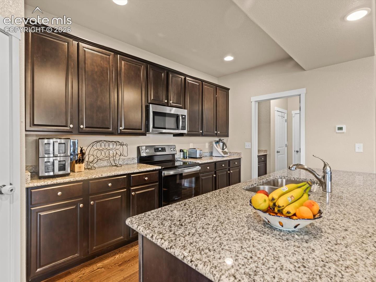 Kitchen featuring extensive dark wood cabinetry, granite countertops, and stainless steel appliances