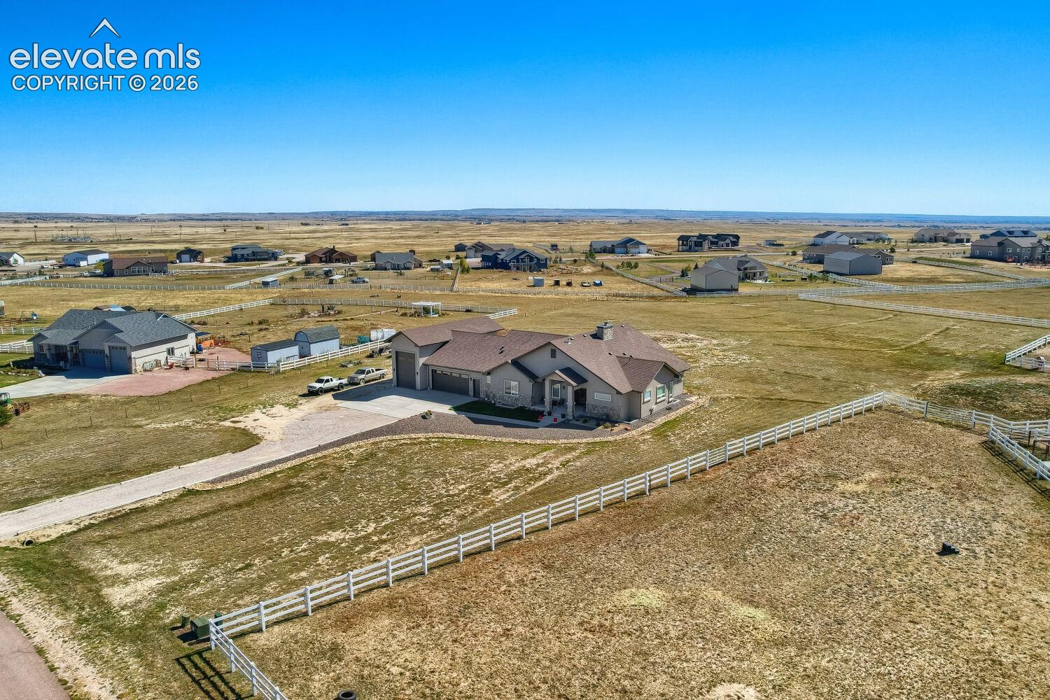 Ranch-style residence featuring a multi-car attached garage, expansive gravel driveway, and a fenced perimeter