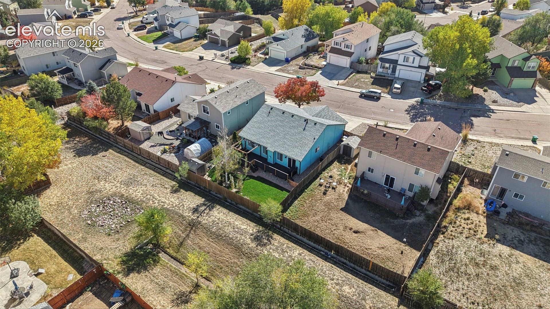 Aerial perspective of a multi-level residence featuring a wooden rear deck, fenced backyard, and attached garage