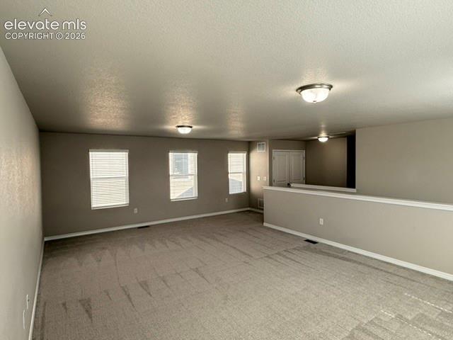 Carpeted open-concept space featuring multiple windows with blinds, neutral wall tones, and recessed lighting fixtures