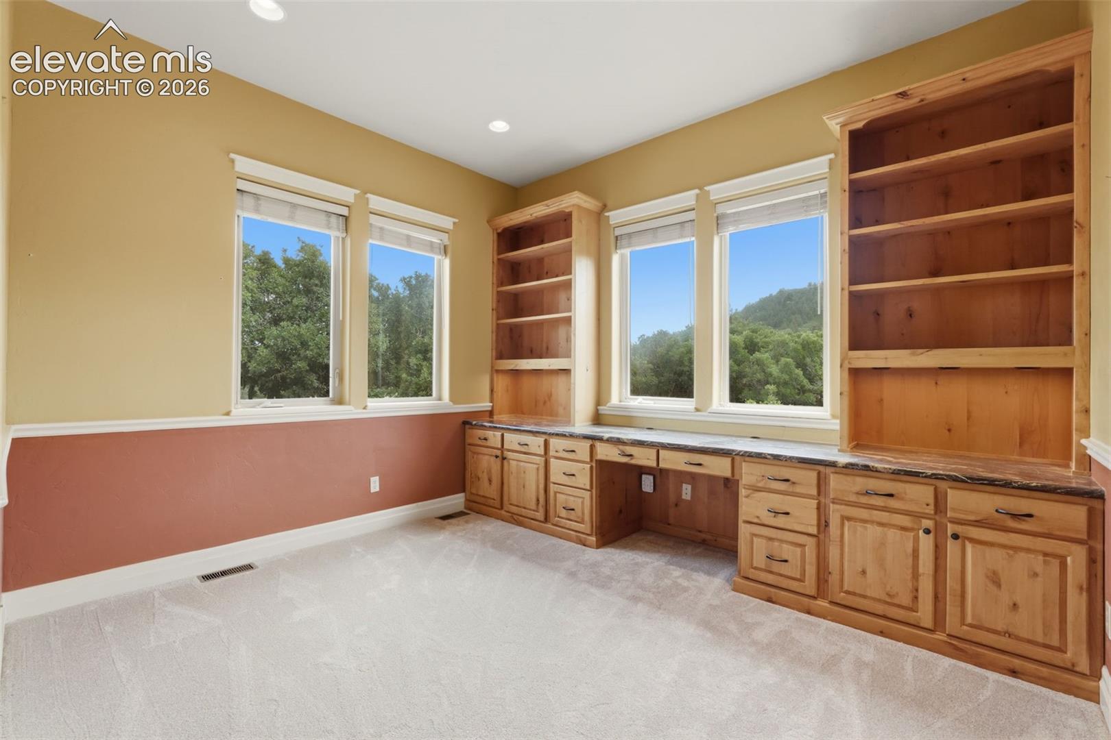 Built-in wood cabinetry with stone countertops and two integrated desks