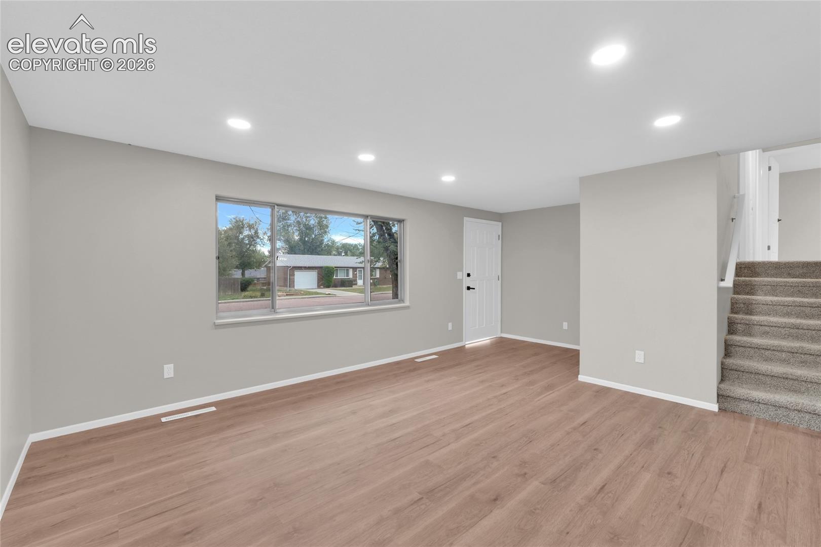 Recessed lighting, wood-finish flooring, light gray wall paint, and white trim