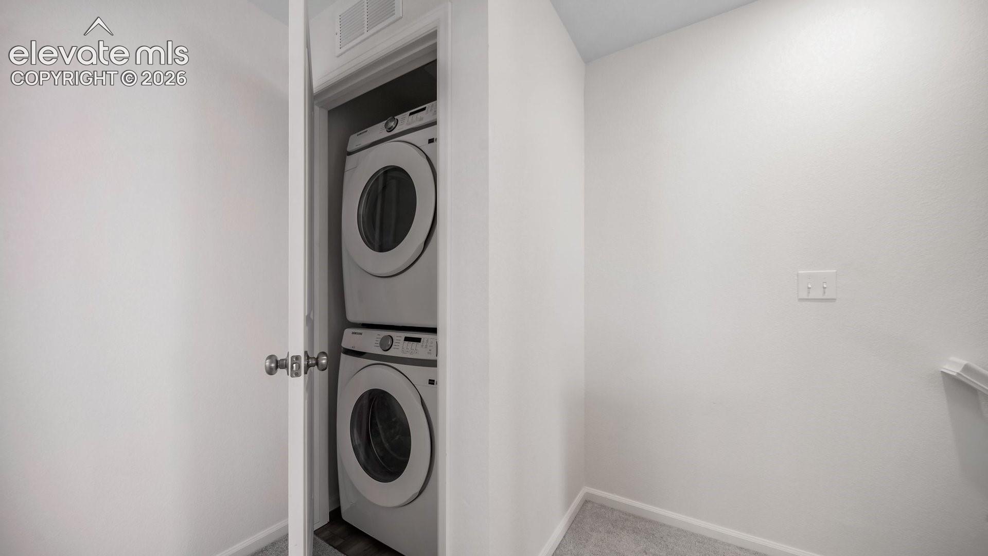 Stacked laundry closet featuring a white door, neutral interior walls, and carpeted flooring
*photos of a model home*