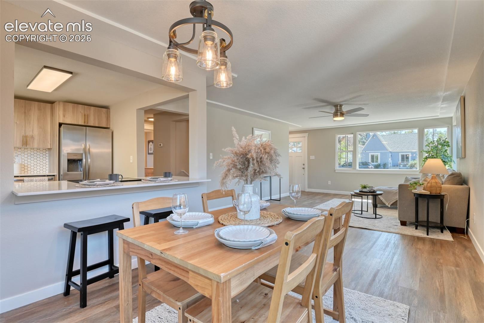 Open-concept living area featuring a breakfast bar, wood-finish flooring, recessed lighting, and a ceiling fan