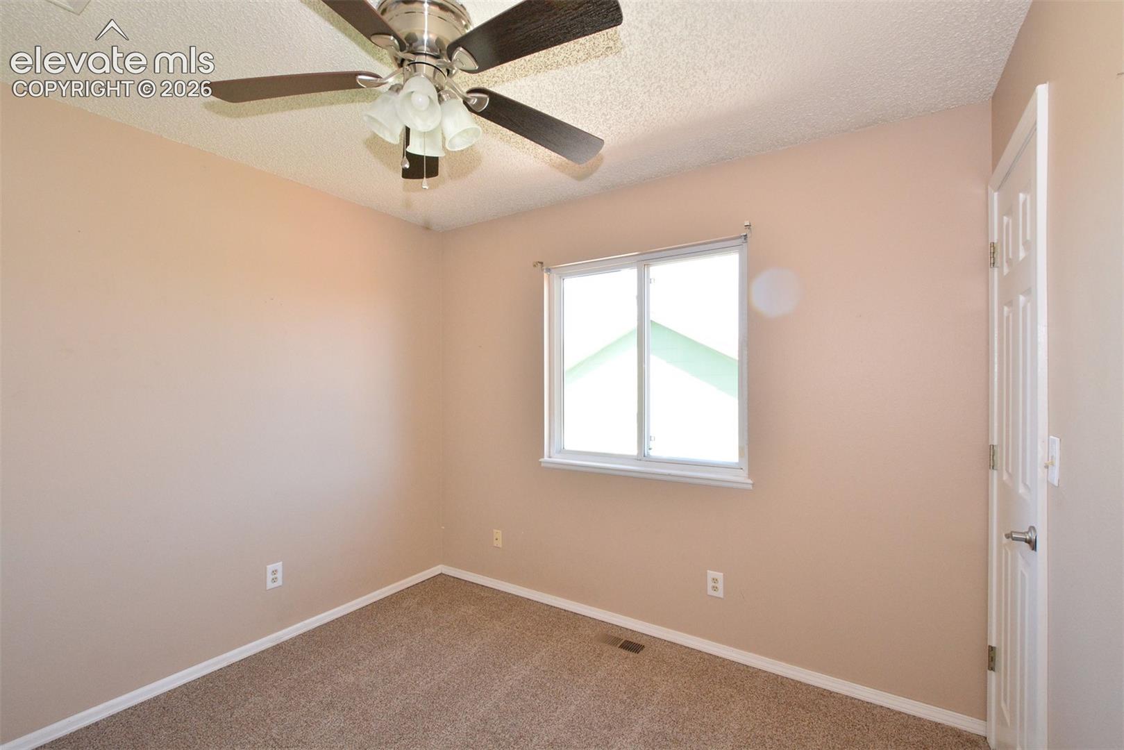 Ceiling fan with integrated lighting, window with white trim, wall-to-wall carpeting, and a white paneled door