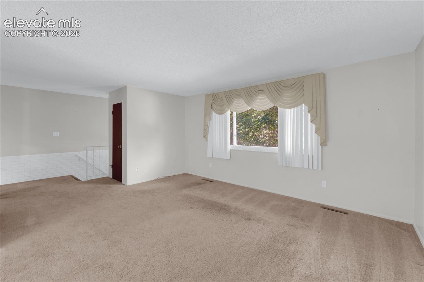 Living room with stairway to entrance and coat closet
