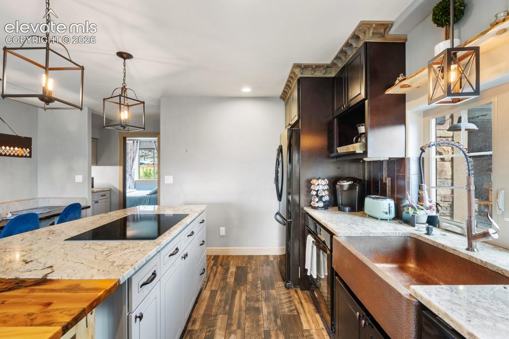 Kitchen featuring a central island with a built-in cooktop, light-toned cabinetry, granite countertops, and wood-finish flooring