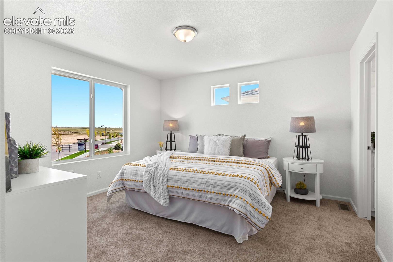 Bright interior featuring a large window, neutral wall paint, and plush carpeting
*photos  of a model home*