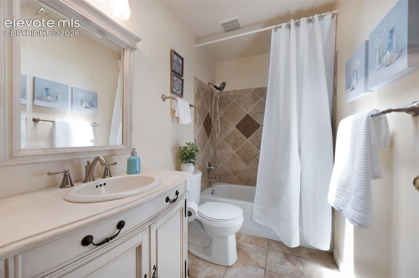 Bathroom with toilet, shower / tub combo with curtain, and vanity. Skylight.