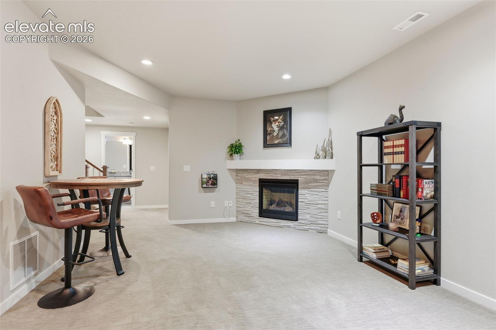 A fireplace with a stacked stone facade and mantel, recessed lighting.