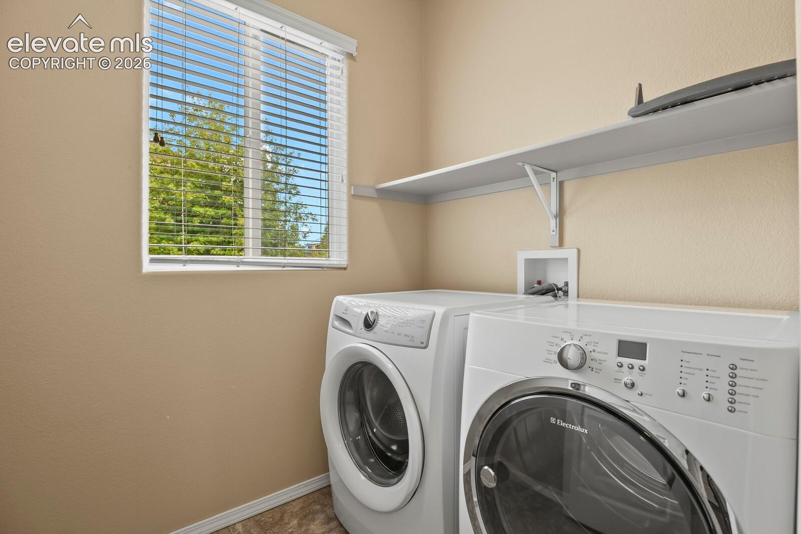 Window with white blinds, neutral wall tones, and overhead shelving