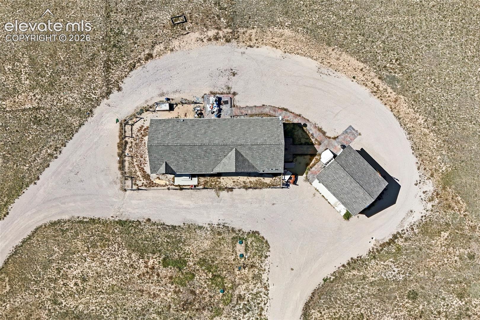 Aerial view of property featuring a detached structure, shingled roofing, and a gravel driveway