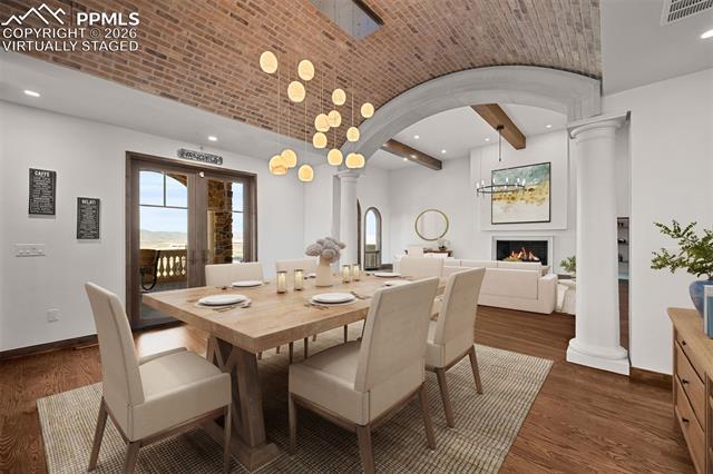 Dining room features a brick barrel ceiling with Italian glass chandelier and walk-out access to the deck for seamless indoor-outdoor dining. Virtually staged.