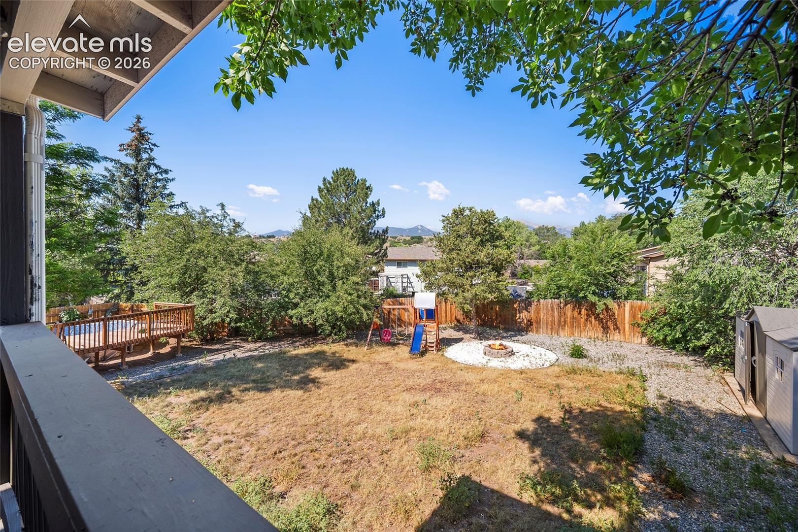 Fenced backyard with mature trees.