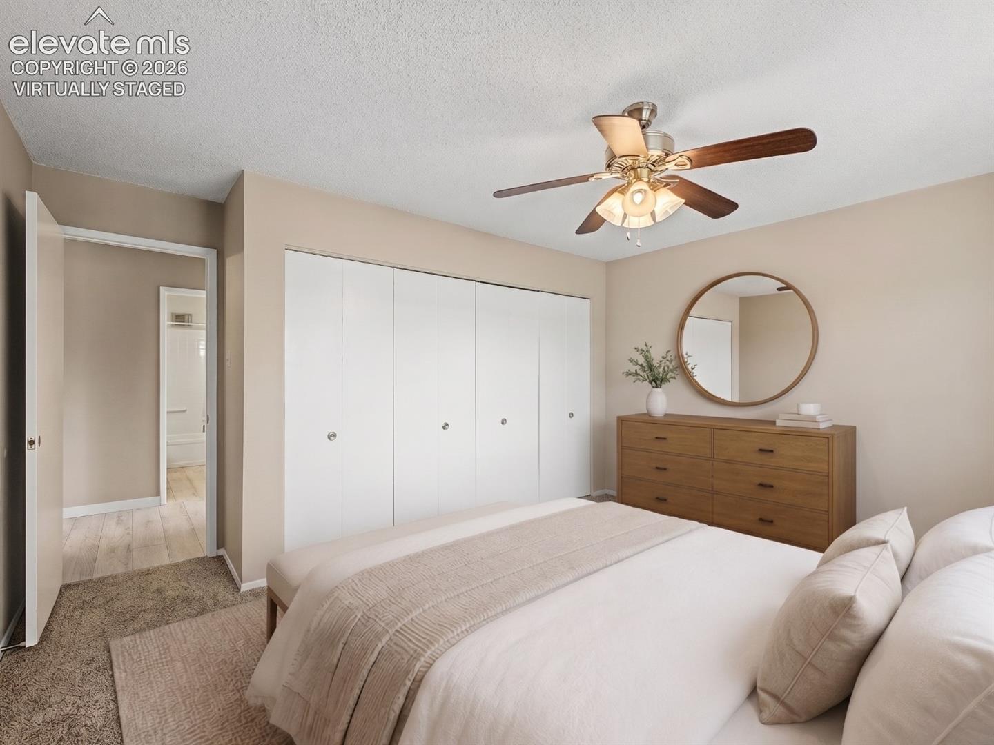 virtually staged Bedroom featuring carpet flooring, a multi-blade ceiling fan with integrated lighting, and bi-fold closet doors