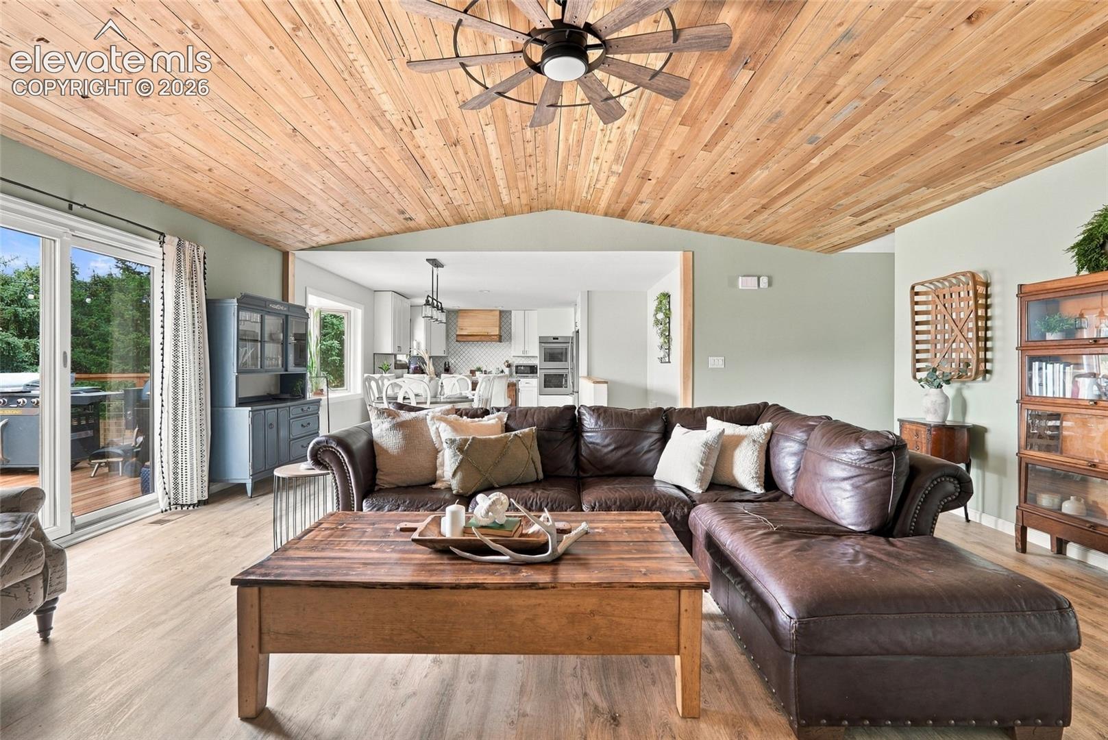 Wood-finish vaulted ceiling with a ceiling fan, light green painted walls, and wood-finish flooring