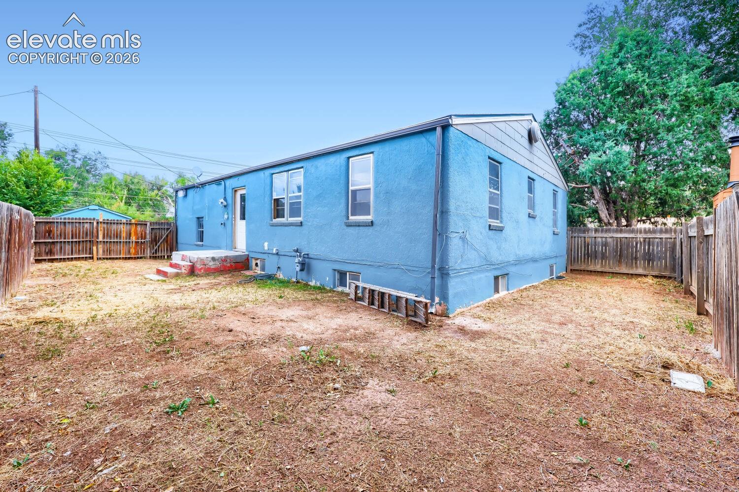 Blue stucco exterior with multiple windows and a wood fence