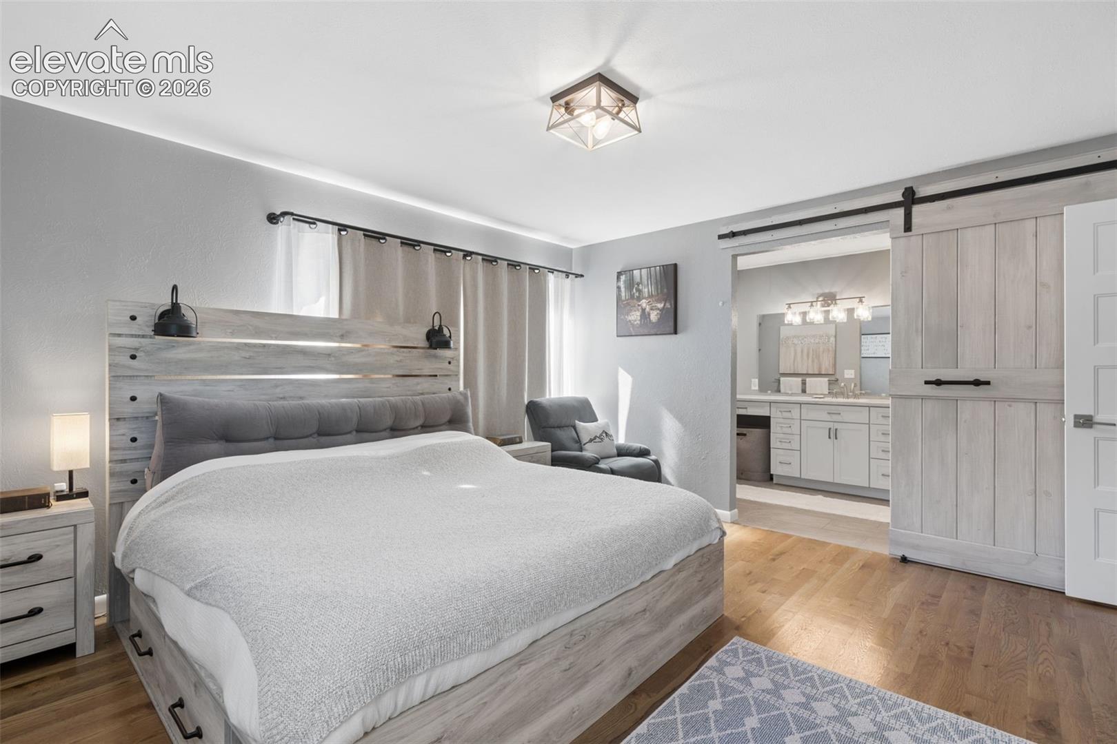 Wood-finish flooring, sliding wood-panel door with matte black hardware, flush-mount geometric ceiling light, and neutral wall tones