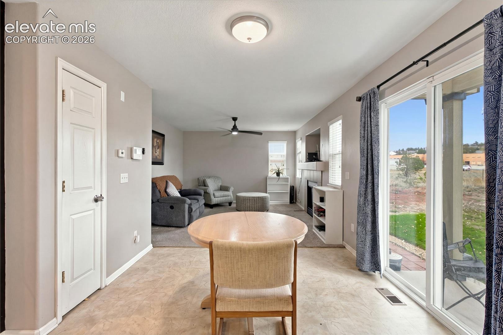 Open-concept room featuring a recessed fireplace, ceiling fan, neutral wall paint, and sliding glass doors leading to an exterior patio area