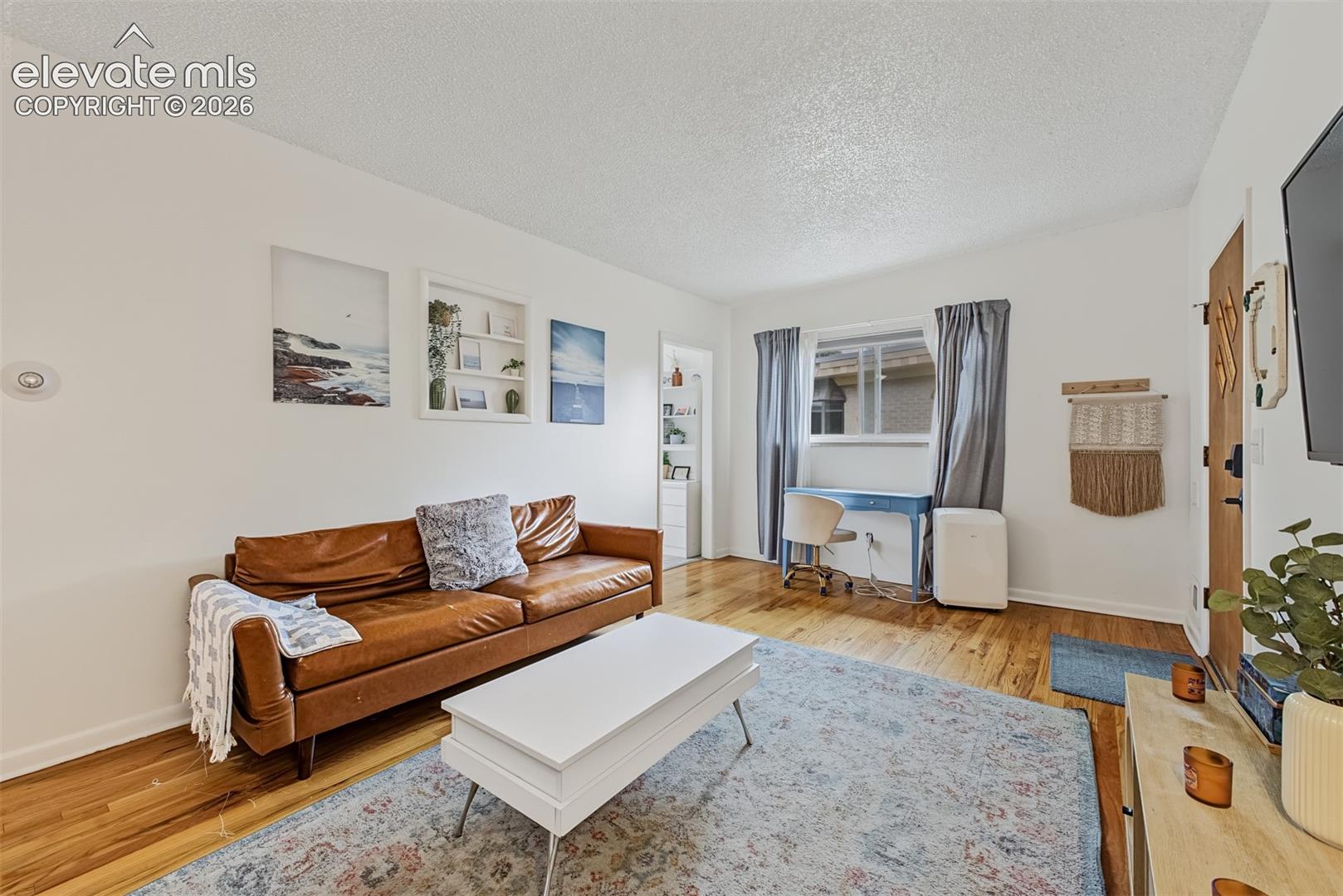 Wood-finish flooring, recessed wall shelving, and a natural light-admitting window