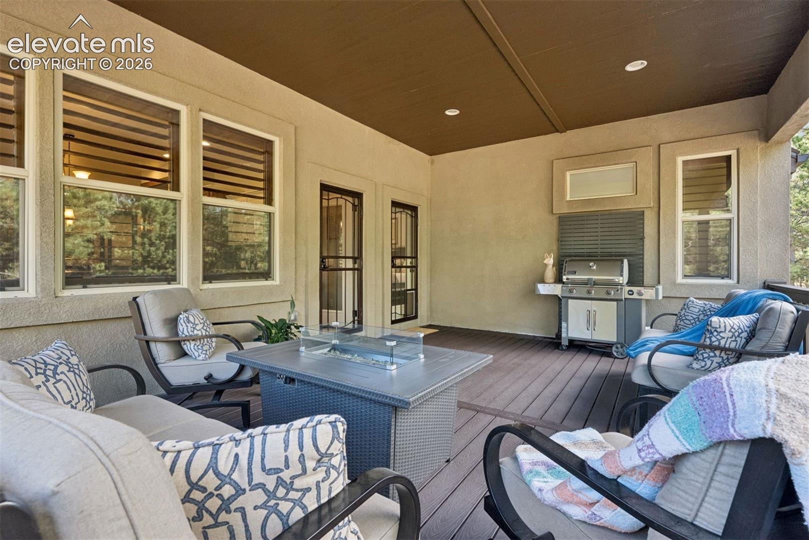 Covered patio featuring composite decking, recessed lighting, integrated exterior gas grill, and multiple glass-paned doors