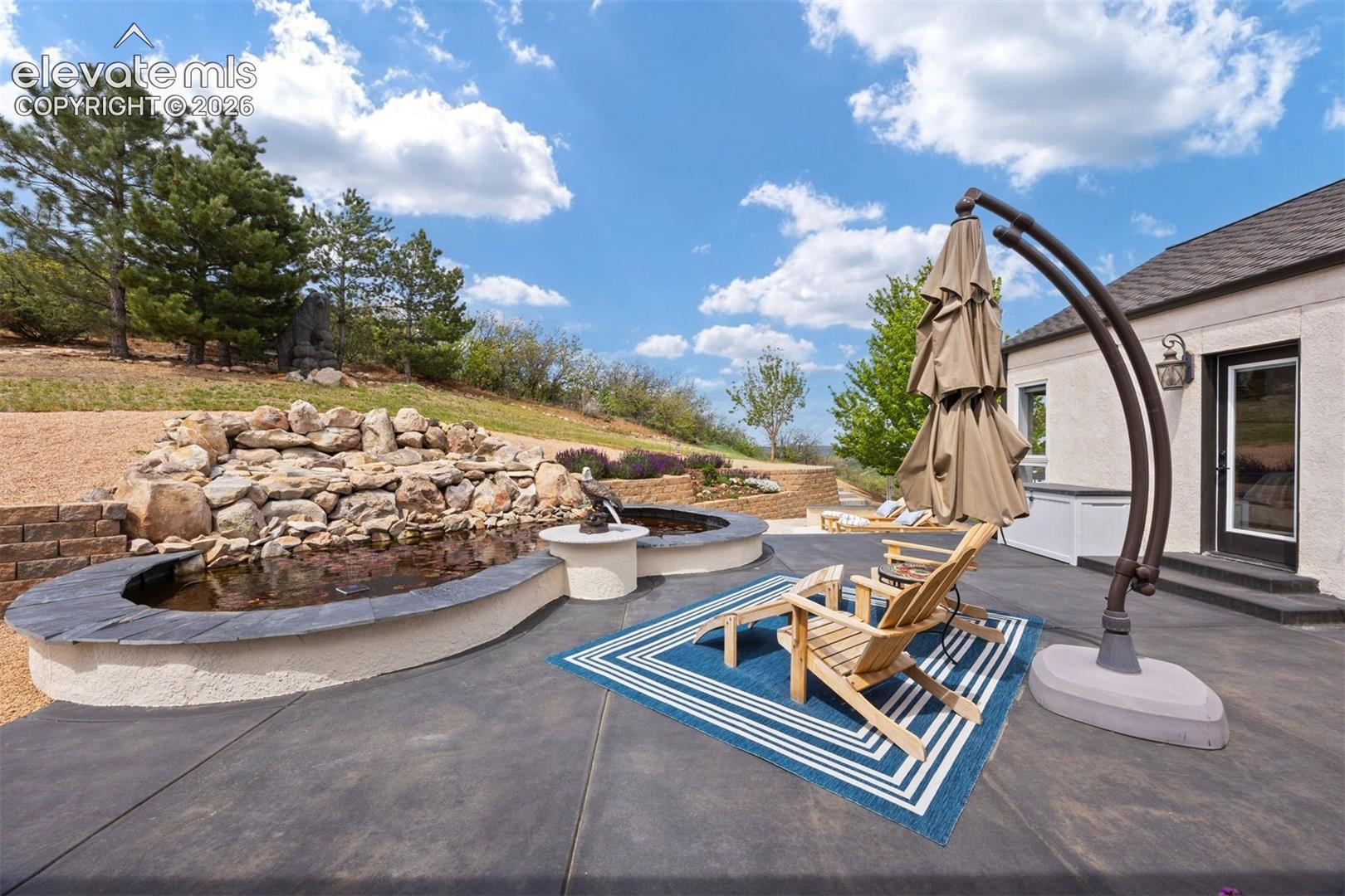 Spacious patio with multiple outdoor seating areas and lush hillside landscaping.