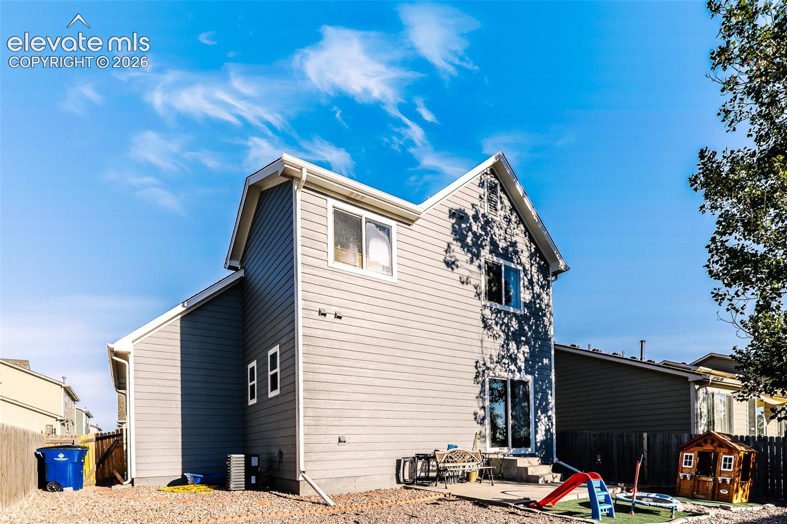 Two-story siding exterior with multiple windows, a sliding glass door, and a concrete patio