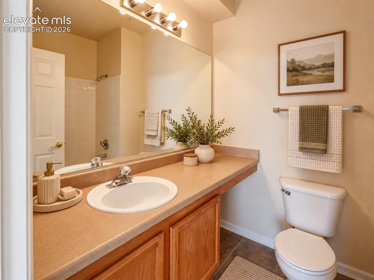 Bathroom featuring a solid-surface countertop, integrated oval sink, full-width vanity mirror, wood-finish cabinetry, and a combination shower and tub enclosure