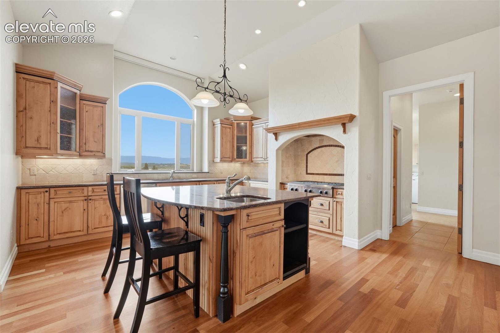 Kitchen featuring wood-finish flooring, custom wood cabinetry, and a large arched window