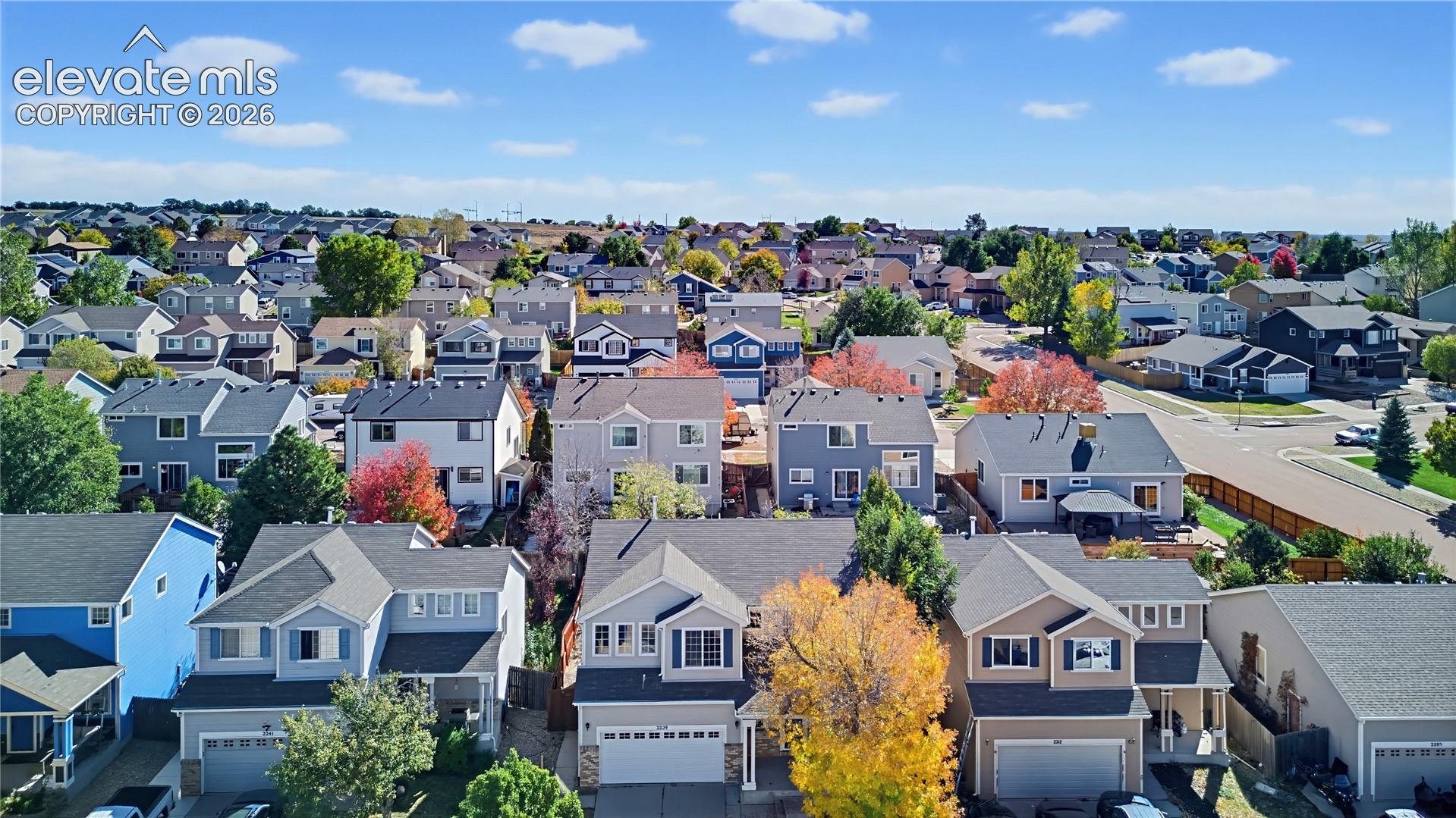 Aerial perspective of a multi-level residential neighborhood featuring asphalt shingle roofs, multi-car garages, and mature deciduous trees