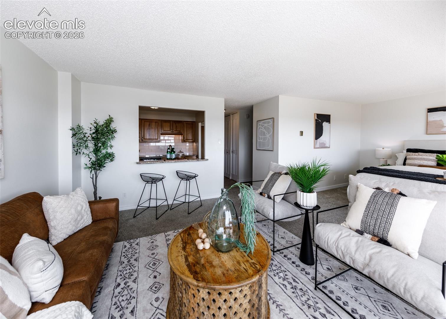 Open-concept interior featuring wall-to-wall carpeting and a kitchen pass-through window with a stone-finish ledge
